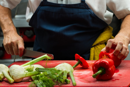 close up of a chef's hands slicing fresh vegetables in a restaurantの写真素材