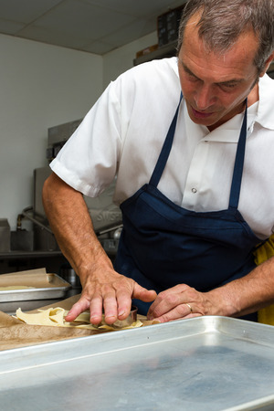 professional chef at work cutting circles of of dough to prepare a fresh dessertのeditorial素材