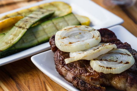 grilled ribeye steak topped with sweet onions and a side of grilled zucchiniの写真素材