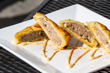 close up of an appetizer in a restaurant consisting of sausage wrapped in a puff pastry then baked...