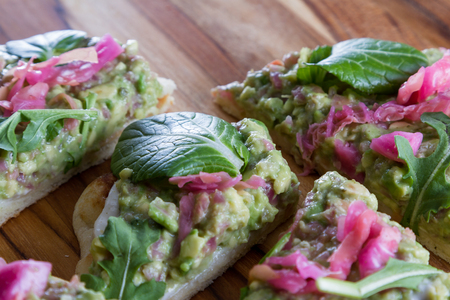 close up of a toasted slice of flat bread topped with a home made spread using avocado and fermented cabbage and then topped with fresh greens.の写真素材