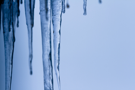 Icicles suspended over a light background with interesting shapes and texturesの写真素材