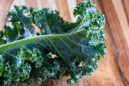 close up of a leaf of fresh organic kale on a cutting boardの写真素材