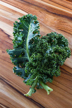 close up of a leaf of fresh organic kale on a cutting boardの写真素材