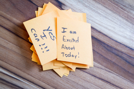 close up of small sticky notes on a wooden desk , all with different positive notesの写真素材
