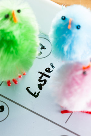 close up of a calendar with the word easter and pastel color fuzzy chicks as a spring concept