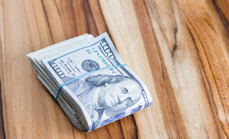 close up of a roll of cash golden in half on a wooden table