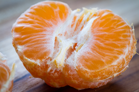 close up of a small orange or tangerine on a wooden cutting boardの写真素材