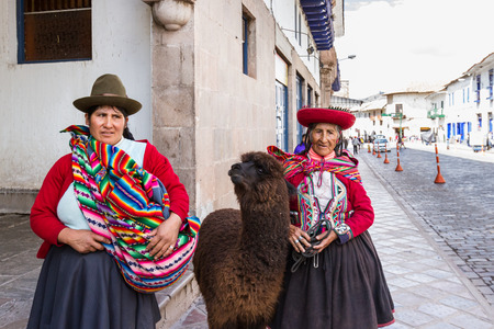 Cusco, Peru - May 14 : Native Peruvian women in Cusco dressed up in traditional colorful clothing with a llama. May 14 2016, Cusco Peru.のeditorial素材