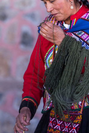 Chinchero Peru -May 18 : Native Cusquena woman dressed in traditional colorful clothing explaining how to spin wool . May 18 2016, Chinchero Peru.のeditorial素材