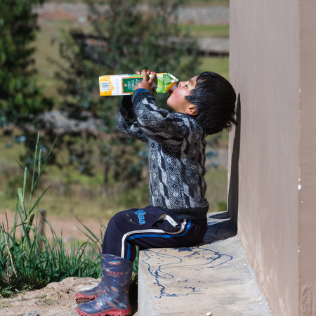 Chinchero Peru -May 18 : Young Andean boy drinking out of a large carton of fruit juice. May 18 2016, Chinchero Peru.のeditorial素材
