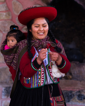 Chinchero Peru -May 18 : Native Cusquena woman dressed in traditional colorful clothing explaining the weaving process with her baby on her back. May 18 2016, Chinchero Peru.のeditorial素材