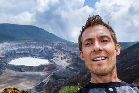 young male taking a self portrait with the Poas Volcano in the Backgroundの写真素材