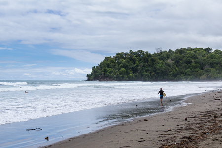 Uvita, Costa Rica - May 04: Lone surfer walking into the ocean. May 04 2016 Uvita, Costa Rica.のeditorial素材