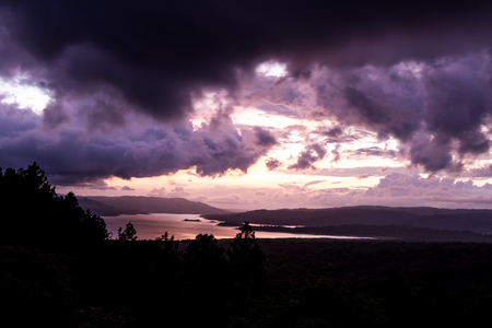 sunsetting behind Lake Arenal viewed from an elevated viewpoint above the tree topsのeditorial素材