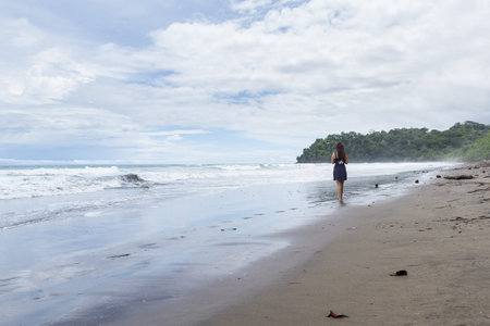 Beautiful young woman walking on a lonely beach in the Costa Rican south pacificの写真素材