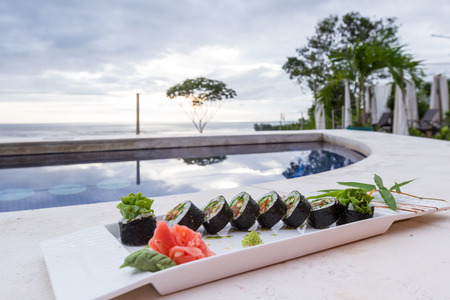 close cup of a vegetarian sushi roll served poolside on a white plateのeditorial素材