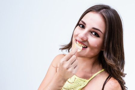 close up of a young beautiful woman eating a potato chip over a white backgroundの写真素材