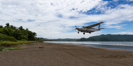 Tambor, Costa Rica - June 22: Sanasa a local airline approaching the runway with a beach scene in...
