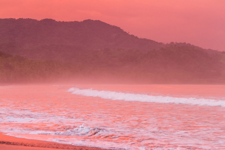 Beautiful sunset on a beach in Costa Rica with amazing vivd color in the clouds and also reflecting on the sand and waterの写真素材