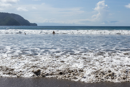 tranquil beach scene with low waves coming in to the dark sandの写真素材