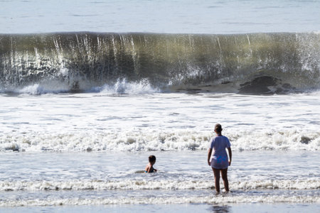 Tambor, Costa Rica - June 22: Large wave breaking infant of a child and her mother. June 22 2016, Tambor, Costa Rica.のeditorial素材