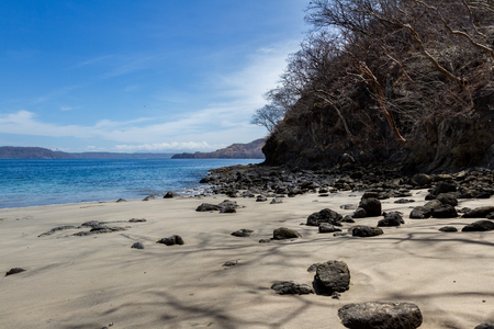 relaxing day at a peaceful beach in costa Rica, with blue water and white sand with a few rocks lying around.の写真素材