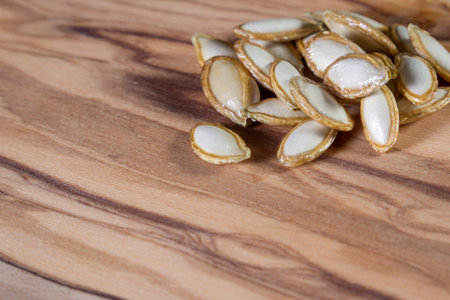 close up of a pile of raw pumpkin seeds on a wooden tableの写真素材