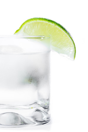 close up of a refreshing cold glass with a clear liquid and a lime wedge on the rimの写真素材