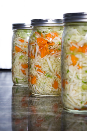 close up of a pint size jar filled with vegetables like carrots and cabbage and a probiotic bacteria to begin the fermentation process. Placed on a granite countertop.の写真素材