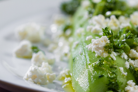 close up of a cucumber and feta cheese salad topped with green onion and parsley dressed with olive oil and lemon juiceの写真素材