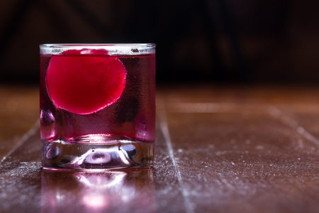 refreshing drink with a red ice ball releasing flavor into the cocktail as it melts and chills the...