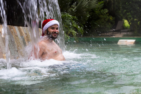 young man relaxing in natural hot springs in Costa Rica wearing a red seasonal hatのeditorial素材