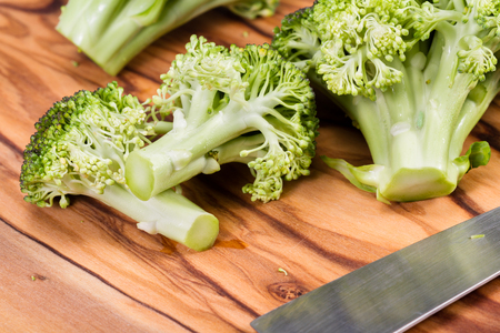 fresh organic broccoli pieces on a wooden cutting boardの写真素材