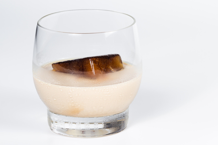 frozen coffee into a cube melting away in a glass with Irish cream making a delicious cocktail isolated on a white backgroundの写真素材