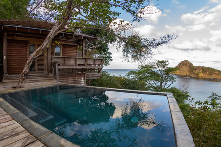 relaxing scene with a calm pool and a wooden deck and building with the pacific ocean in the backgroundのeditorial素材