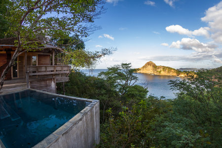 relaxing scene with a calm pool and a wooden deck and building with the pacific ocean in the backgroundのeditorial素材
