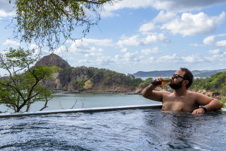 man relaxing in a  calm pool with an amazing view of the pacific ocean