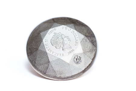 Diamond shape silver coin with a  diamond embedded on to the side of the coinの写真素材
