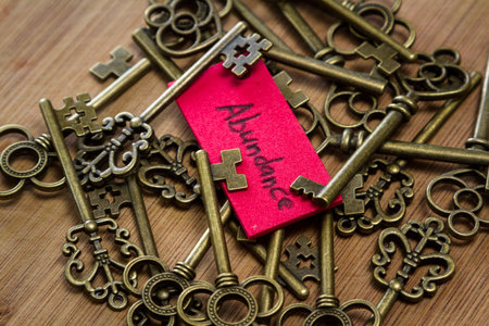 concept image using old keys and a tag with the word abundance handwritten on it over a wooden...