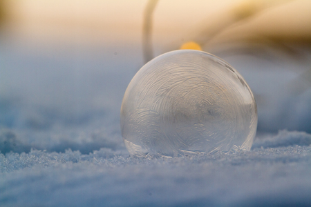 Close up of a small soap bubble freezing rapidly due to extreme cold temperatures in winterの写真素材