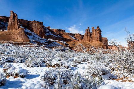 Three Gossips feature with snow on the ground and blue sky in Arches National Parkの写真素材