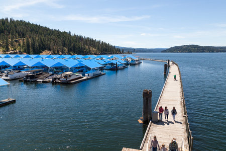 CDA, Idaho - June 12: Families walking on the boardwalk with the covered marina and tubes hill in the background. June 12, CDA, Idaho.のeditorial素材
