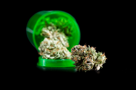 Close up of a green prescription bottle with cannabis buds isolated on a black backgroundの写真素材