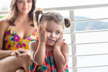little girl making faces and her mother smiling in the background