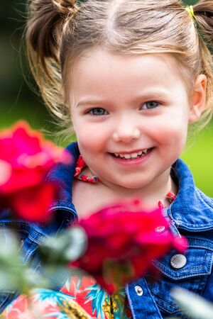 portrait of a young and adorable little girl in  a natural outdoor setting with out of focus rosesの写真素材