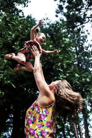 image of a young mother lifting her baby girl up to the trees with a bit of  edited with a bit of...