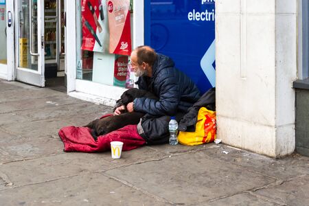 London  - September 05 2019: Homeless man with his dog with people walking past on the sidewalk, London September 05,  2019のeditorial素材