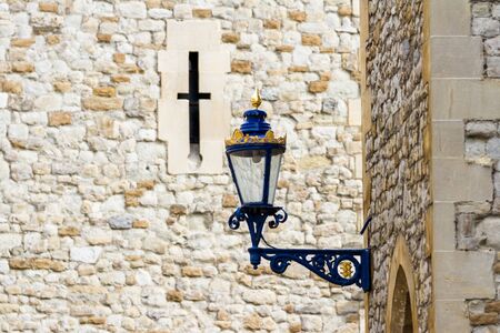 Blue street light in the Tower of London with gold leafing and an arrow slit in the backgroundの写真素材