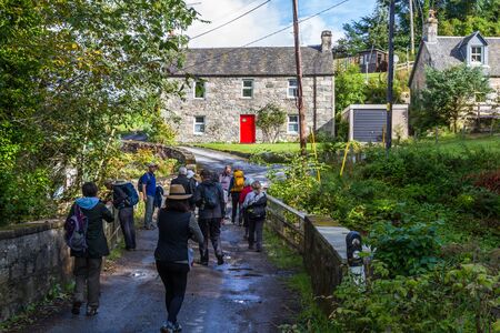 Pitlochry Scotland  - September 10 2019: Group of people walking by the old Post Office identified by the red door, UK September 10,  2019のeditorial素材